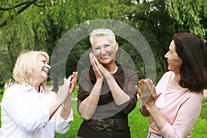 Three female friends in the park celebrate a birthday. Clap your hands, congratulate, rejoice.