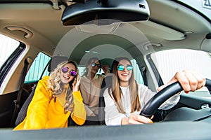 Three female friends in sunglasses enjoying traveling at vacation in the car