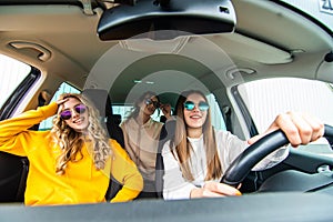 Three female friends in sunglasses enjoying traveling at vacation in the car