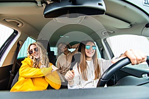 Three female friends in sunglasses enjoying traveling at vacation in the car