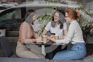 three female friends are talking in a coffee shop and drinking tea, moral support and caring friendship. mental health
