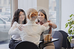 three female friends are talking in a coffee shop and drinking tea, moral support and caring friendship. mental health