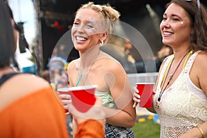 Three Female Friends Wearing Glitter Having Fun At Summer Music Festival Holding Drinks