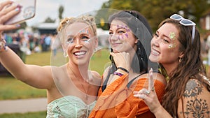Three Female Friends Wearing Glitter Posing For Selfie At Summer Music Festival 