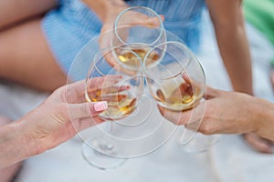 Three female hands with glasses of white wine. Toast, congratulations on an outdoor picnic. The concept of relaxation