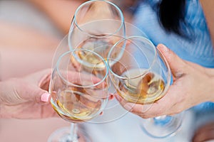 Three female hands with glasses of white wine. Toast, congratulations on an outdoor picnic. The concept of relaxation