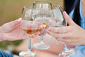 Three female hands with glasses of white wine. Toast, congratulations on an outdoor picnic. The concept of relaxation