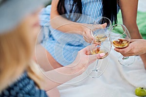 Three female hands with glasses of white wine. Toast, congratulations on an outdoor picnic. The concept of relaxation