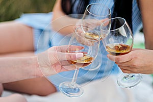 Three female hands with glasses of white wine. Toast, congratulations on an outdoor picnic. The concept of relaxation