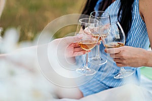 Three female hands with glasses of white wine. Toast, congratulations on an outdoor picnic. The concept of relaxation