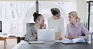 Three female mixed race employees discussing corporate software.