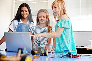 Three Female Students Building And Programing Robot Vehicle In After School Computer Coding Class