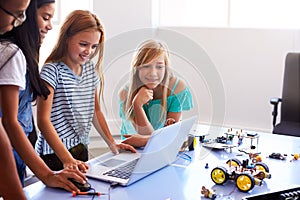 Three Female Students With Teacher Building Robot Vehicle In After School Computer Coding Class