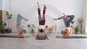 Three female yogis doing the scorpion pose in a yoga studio. team yoga