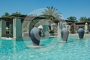 Three fictile ewers standing in line at swimming pool in arabic luxury desert resort photo