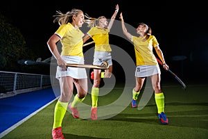 Three field hockey players celebrate the victory