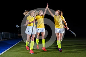 Three field hockey players celebrate the victory