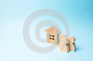 three figures of people and a wooden house on a blue background. The concept of affordable housing and mortgages for buying a home photo