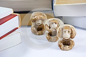 Three figurines of monkey with many thick books