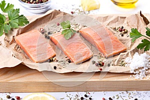 Three fillets of fresh raw salmon fish with spices and herbs on cutting board