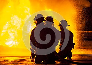 Three firefighters kneeling in front of fire