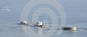 Three fishing boats in ice captive in sun shining day