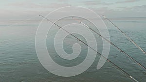 Three fishing rods over calm water surface of Caspian sea. Man`s hobby.