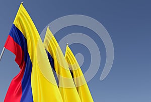 Three flags of Colombia on a flagpole on a blue background. Place for text. The flag is unfurling in wind. Bogota. South America.