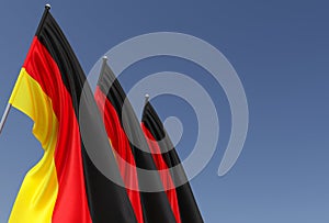 Three flags of Germany on a flagpole on a blue background. Place for text. The flag is unfurling in wind. German. Europe, Berlin.