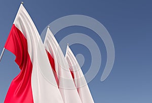 Three flags of Poland on a flagpole on a blue background. Place for text. The flag is unfurling in wind. Polish. Europe, Warsaw.