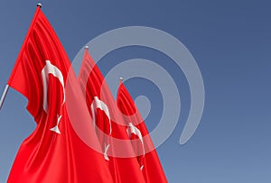 Three flags of Turkey on a flagpole on a blue background. Place for text. The flag is unfurling in wind. Turkish. Ankara, Istanbul