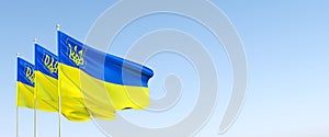 Three flags of Ukraine on flagpole. Blue and yellow Ukrainian flag with coat of arms. State symbols of Ukraine. Trident. The flag