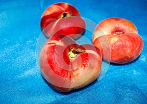 Three flat peaches on the table on a soft blue background