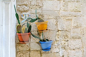 Three flower pots with flowers hanging from the stone facade of an Italian house