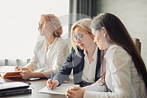 Three focused business women working together, brainstorming in office.