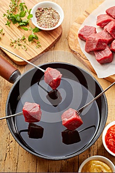 Three fondue forks with cubes of raw meat