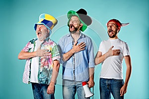 The three football fans singing the national anthem over blue