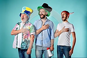 The three football fans singing the national anthem over blue