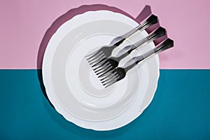 Three forks on a white plate on a colored
