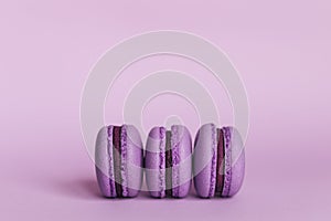 Three french macarons on a purple background. Place for text