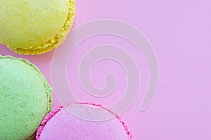 Three french traditional bisquits called macaroon in the corner on pink background. Green