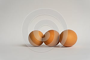 Three fresh brown chicken eggs in a row on grey background. Easter holiday