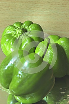 Three fresh capsicum on a reflective base