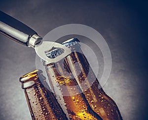 Three fresh cold beer ale bottles with drops and stopper open with bottle opener