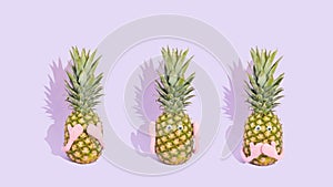 Three fresh pineapples like three wise monkeys. Concept of see no evil, hear no evil and speak no evil. Summer fruit on pastel