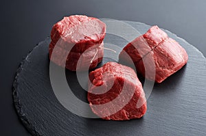 Three fresh raw Prime Black Angus beef steaks on stone background