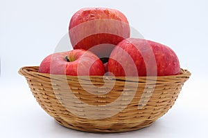 Three fresh red aplles in a basket isolated in white backgroumd.