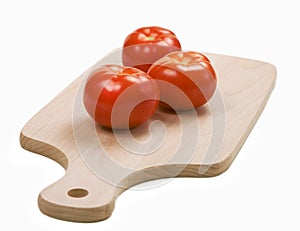 Three fresh red tomatoes on cutting board