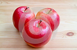 Three of fresh ripe red apple isolated on wooden table