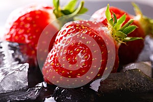Three fresh strawberries on slate stone with ice